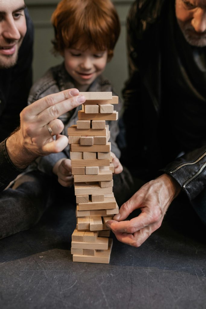 Father, son, and grandfather bonding over a game of Jenga indoors, fostering family connection.